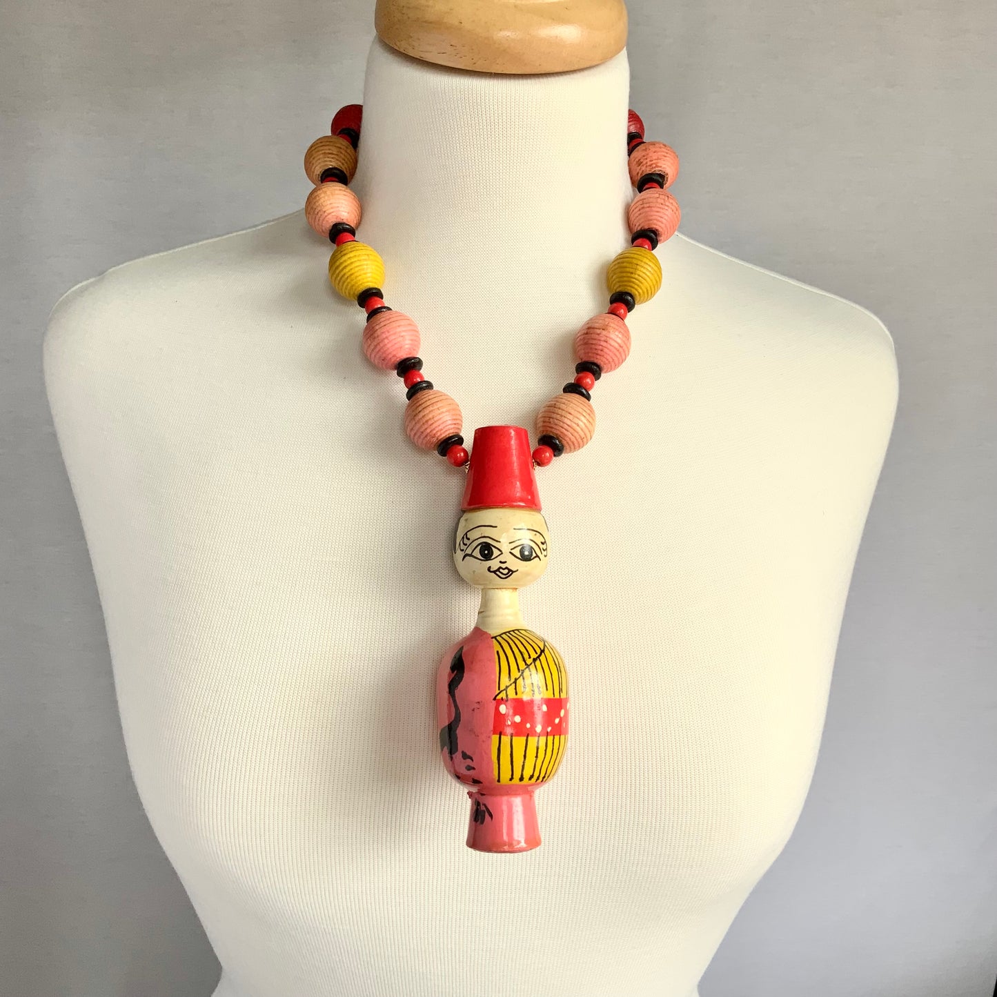 Wood Folk Art Doll Wearing on Pink and Yellow Necklace