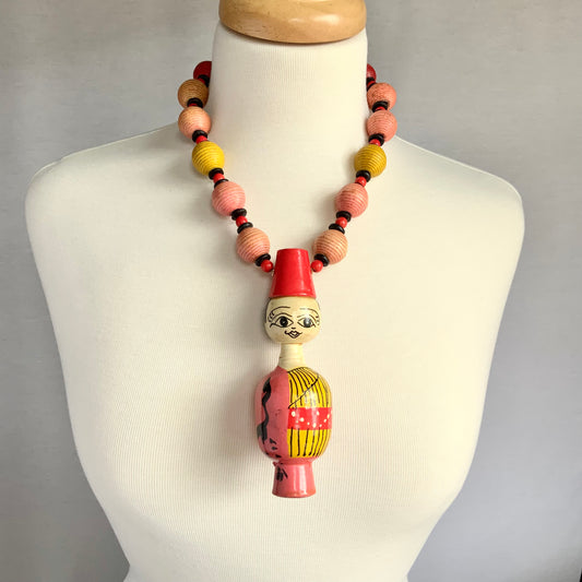 Wood Folk Art Doll Wearing on Pink and Yellow Necklace